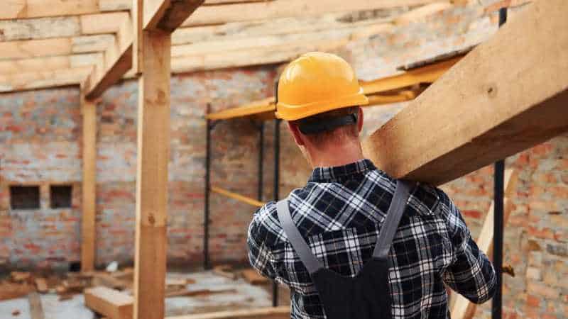 Porteur de bois dans un chantier de construction en bois, portant un casque de sécurité.